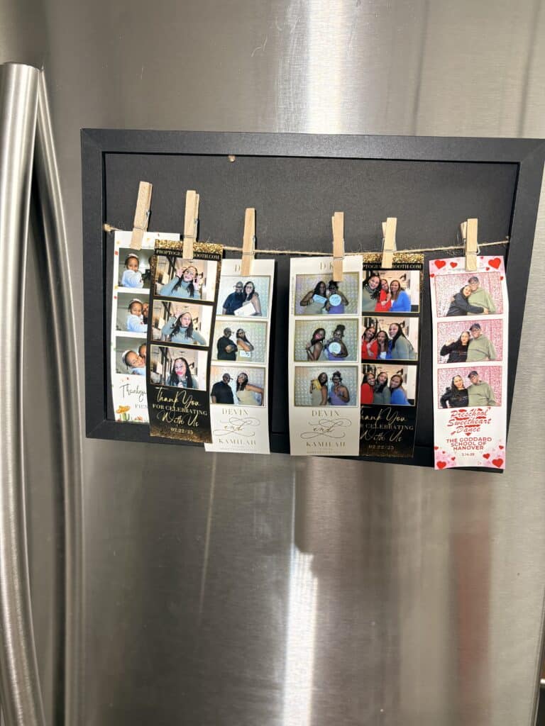 Photo booth strip printouts displayed on a refrigerator as lasting wedding keepsakes.