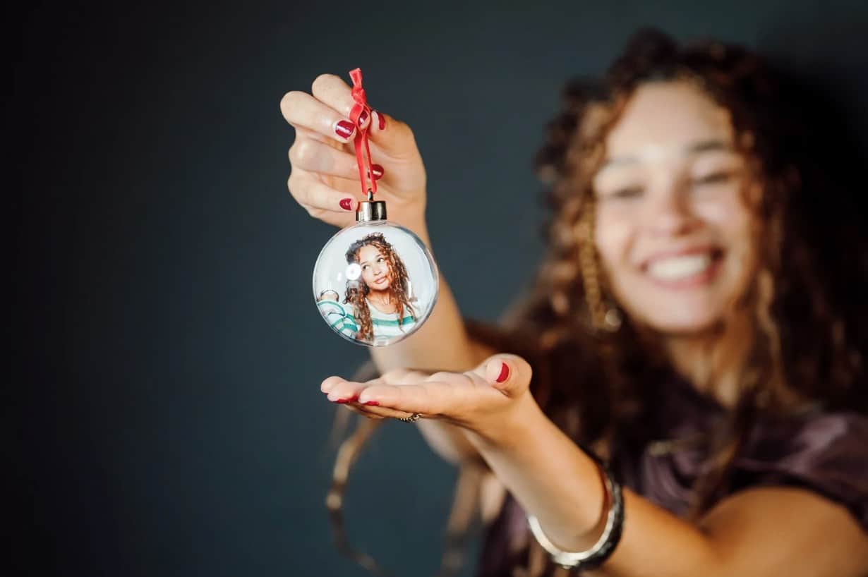 A guest proudly holds a custom holiday photo ornament featuring a personalized portrait inside a clear ornament. Available as part of Proptography Co's 2026 Holiday Experience Collection, these unique keepsakes are perfect for corporate holiday parties, employee appreciation events, client gifts, and seasonal celebrations throughout Baltimore and the DMV.