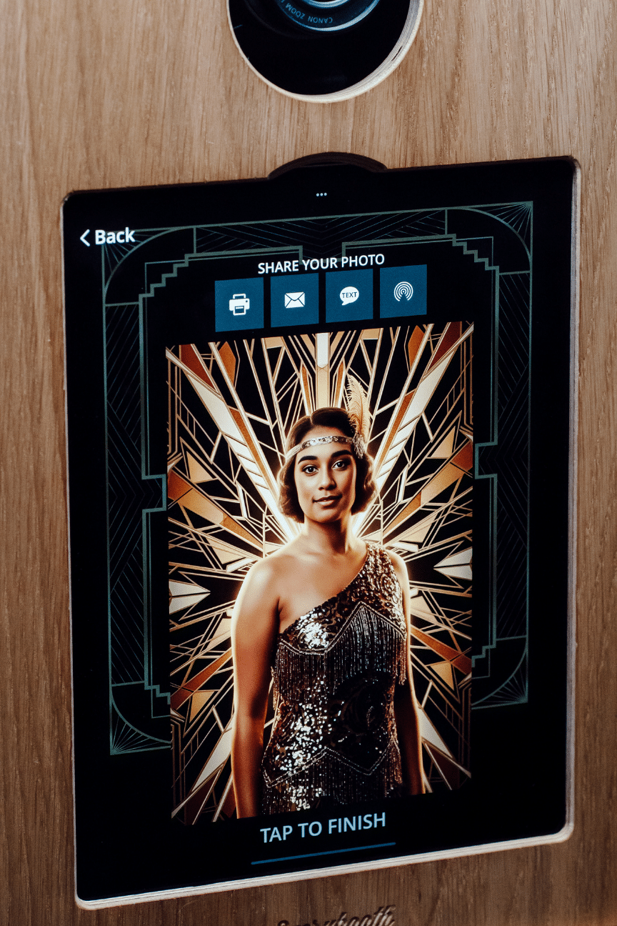 Guest photo booth screen displaying a Roaring 20s AI portrait result, showing a woman in a sequined flapper dress with an art deco gold and black starburst background, from Proptography Co's AI Portrait Studio